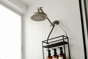 Verkalkter Duschkopf wird mit Reinigungsmittel eingesprüht